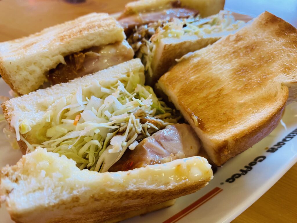 コメダ珈琲の人気商品「網焼きチキンサンド」。分厚いチキンと照り焼きソースがパンにしみ込んでいる様子。