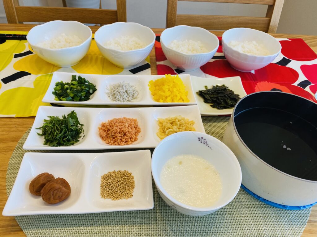 食卓に白ご飯とお茶漬けの具材10種、かにつゆが準備された様子。