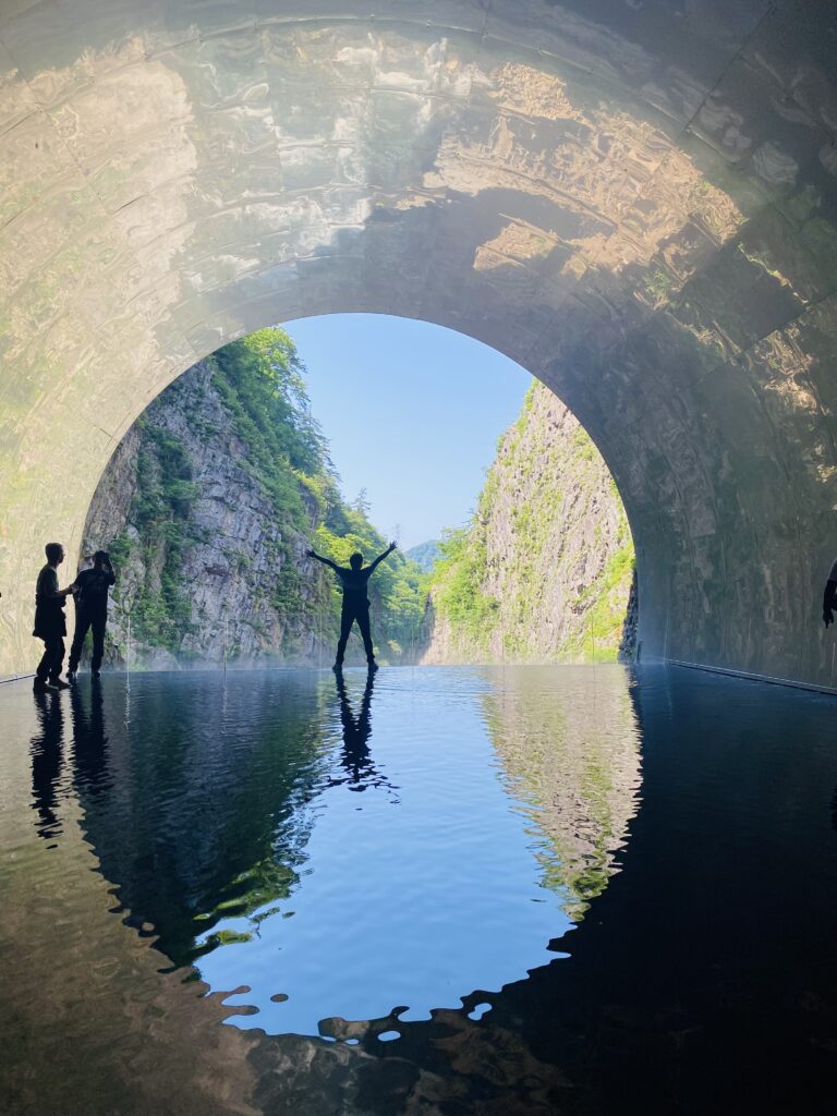 清津峡のパノラマステーションにて水盤鏡でポーズをとる旦那さん